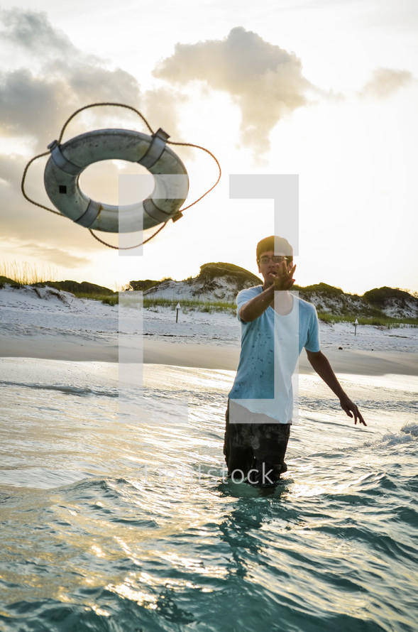 man tossing a life preserver into the ocean