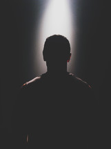 silhouette of a man standing in light 
