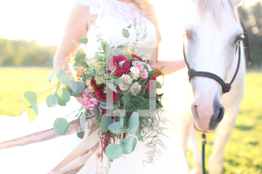 bride with a bouquet and her horse 