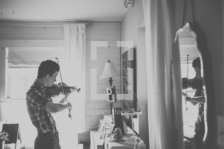 a teenage boy playing a fiddle in a mirror 
