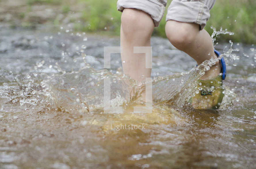 a toddler splashing in a puddle 