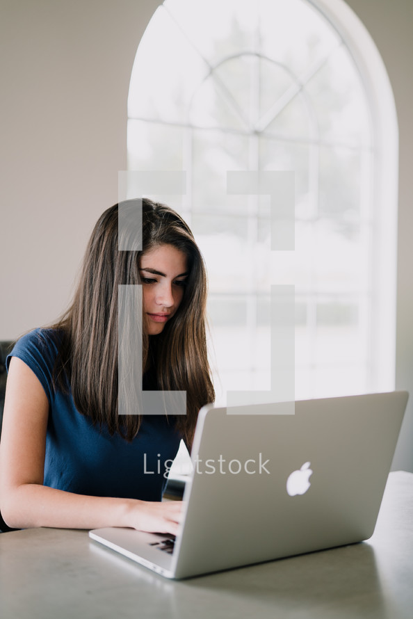 teen girl sitting at a desk with a laptop computer 