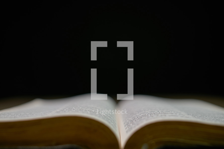 Open bible up close against a black background