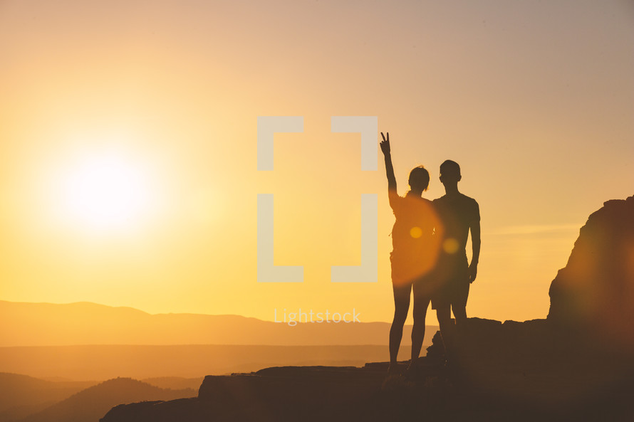 a couple on a mountains edge at sunset 