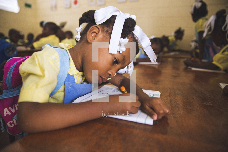 Girl doing her schoolwork on a wooden table.