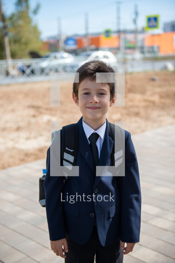 portrait of a boy in dress clothes with a book bag 