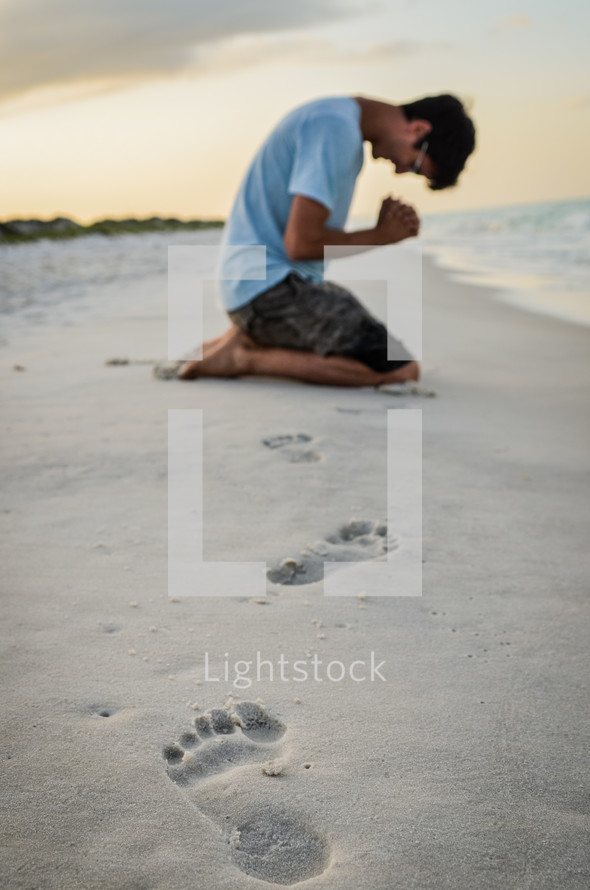 man in prayer on a beach