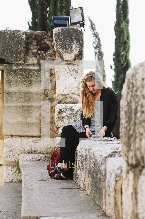 A woman sitting on a stone wall reading a Bible in Jerusalem