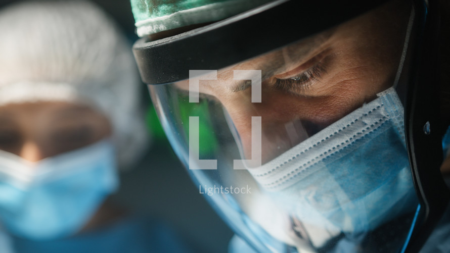Surgeon with visor and surgical mask Operates A Contagious Disease