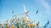 Spinning Wind turbine over yellow flower ecology concept