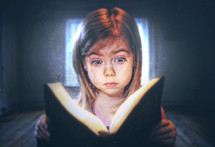 A little girl reading with a surprised expression