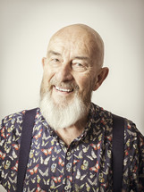 an elderly man in suspenders smiling 