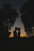 silhouette of a bride and groom kissing at sunset
