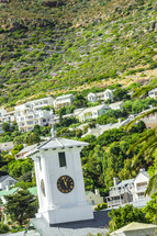 Clock tower and homes on a steep hillside. 