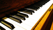 A piano Keyboard with black and white keys stretching out against a wood grain piano body for a church pianist / musician to play during worship and praise time. 
