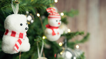 Small polar bear and snowman decorating a Christmas tree