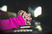 girl's praying hands over a guitar 