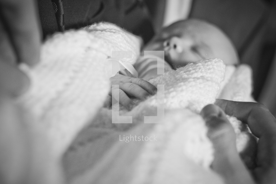hands on swaddled sleeping newborn