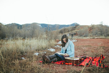 plaid blanket, blanket, reading, woman, sitting, outdoors, guitar 