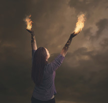 Woman with arms raised in praise, with fire coming from her hands.