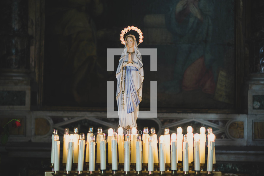 candles around a statue of Mary 