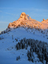 Mountain peak with sharp edges in warm sunrise light. Cold winter morning over a snow covered mountain.