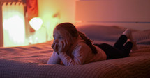 a little girl watching tv on the bed 