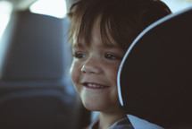 smiling child in the backseat of a car 