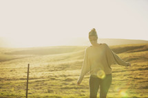 a woman standing outdoors in the countryside at sunset 