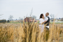 couple standing in a field hugging 