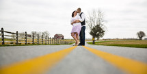 couple hugging standing in the middle of a road 