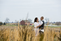 couple hugging in a field on a farm 