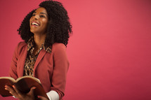 African American woman reading a Bible - pink background 