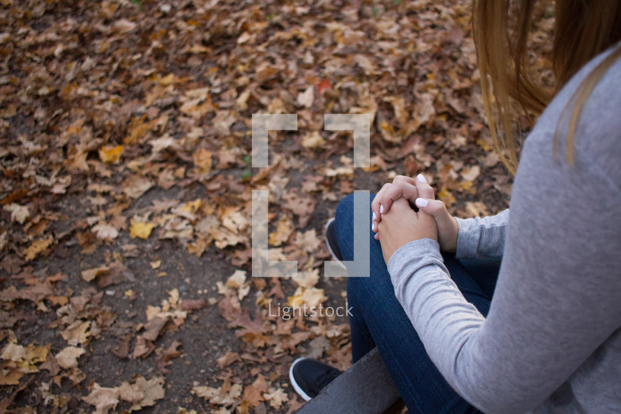 a woman sitting outdoors in fall praying 