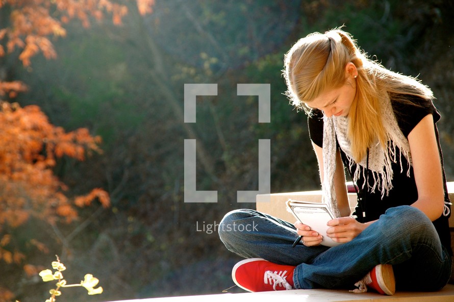 a teen girl holding a Bible with head bowed in prayer 