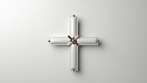 A modern small cross in white ceramic and gold metal material. Set against a white studio background,