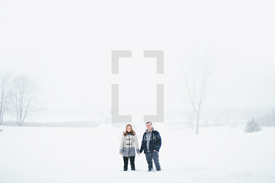 a couple standing holding hands in the snow 