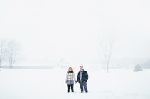 a couple standing holding hands in the snow 