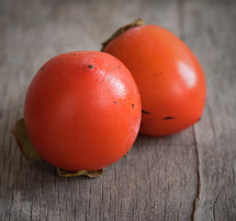Two red tomatoes on a wooden table.