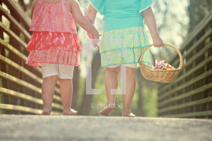 sisters walking bare foot holding hands with a basket