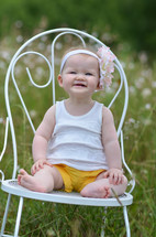 toddler girl sitting on a white chair 
