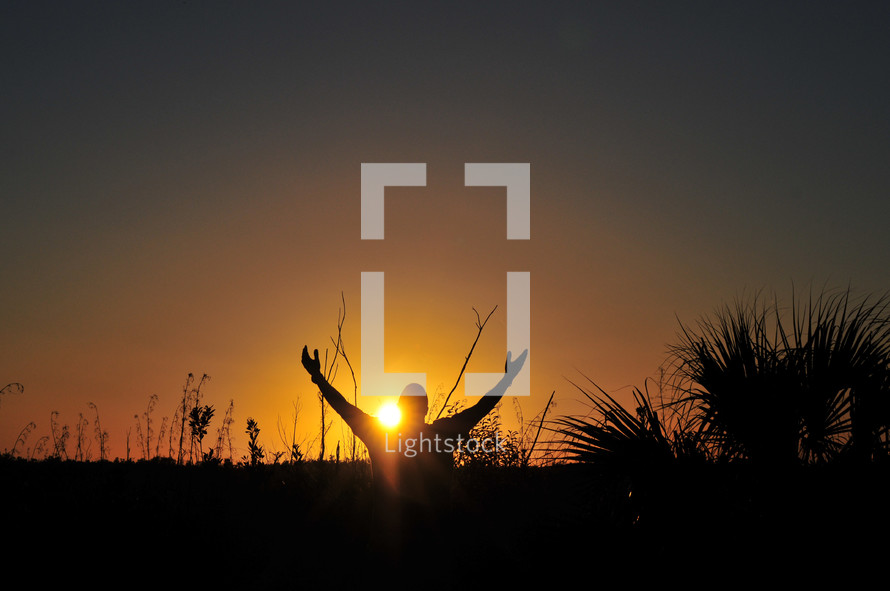 man with Hands Raised to the Lord at Sunset