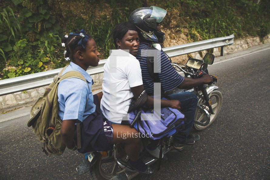 Girls traveling on the back of a motorcycle.