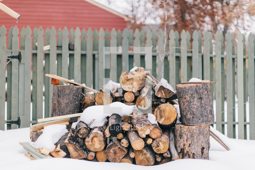 snow and axes near stack of firewood 