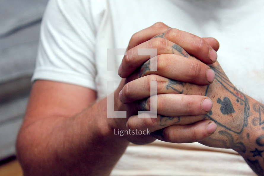 tattooed hands praying 