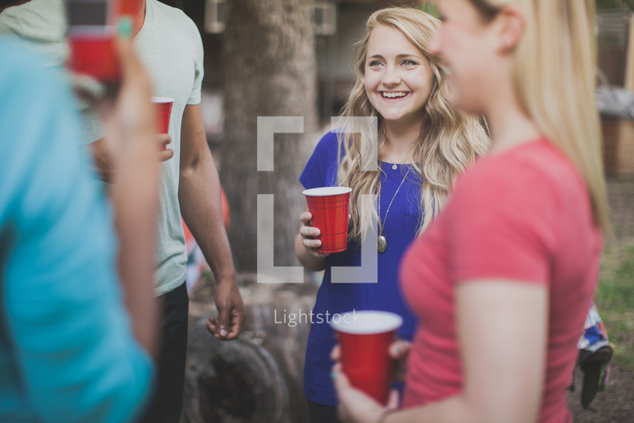 friends holding red cups and talking at a cookout 
