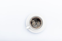 white cup with saucer and coffee on a white background with copyspace