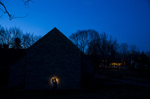 couple hugging in front of a barn under a spotlight 