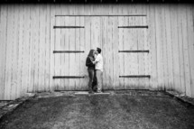 couple kissing in front of a barn 