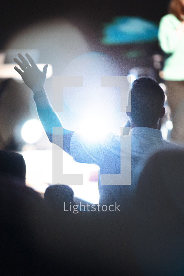 man with hands raised at a worship service 